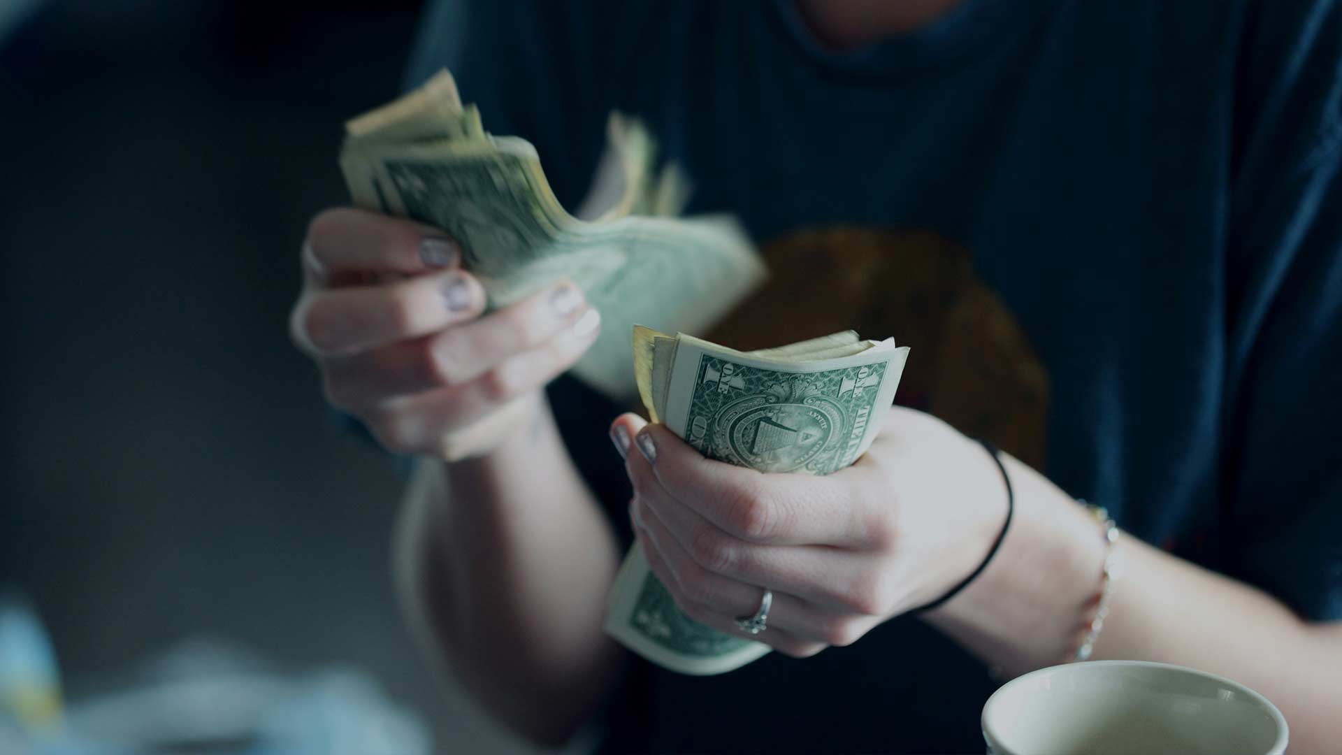 Picture of a woman's hands as she counts $1 bills