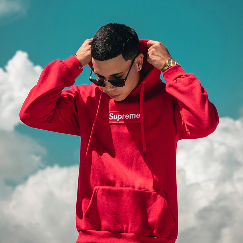Young man wearing a red hoodie with the Supreme logo across the chest